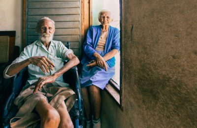 An elderly couple sitting by a window, capturing a serene moment indoors with natural light.