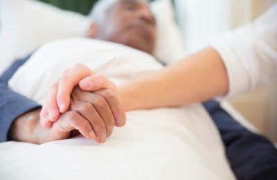 A comforting gesture as a hand holds another in a hospital setting, symbolizing care and support.